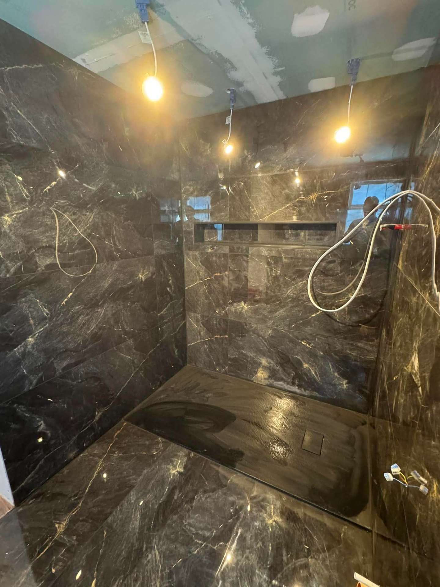 Dark veined marble walk-in shower, fully tiled with linear niche